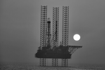 Black and white sunset view of oil drill