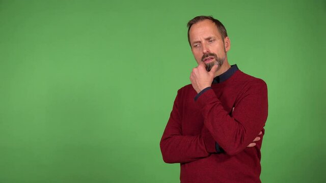 A middle-aged handsome Caucasian man thinks about something - green screen background