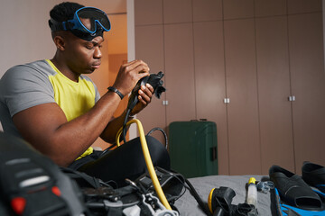 Mixed-race man is adjusting scuba diving equipment