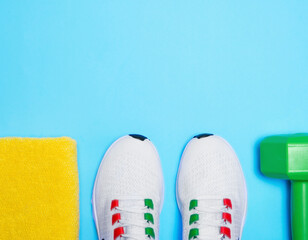 Set of athlete sneakers, dumbbells and on light blue background