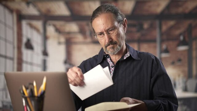 Angry stressed businessman opening envelope reading bad news in mail letter. Mad man feels frustrated about high bills, dismissal notice, bank debt, tax invoice or mistake sits at home office desk.