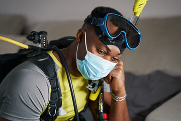 Depressed scuba diver sitting at home in gear
