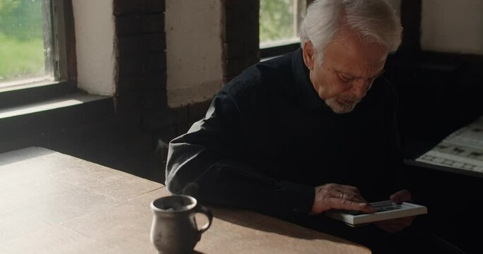 Sad old gray haired man looks to the portrait of lost close friend. Sorrow, depression and mental breakdown, 4k 60p Prores