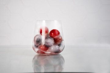 Frozen berries in ice cubes covered with hoarfrost in glass. Homemade food. Top view.