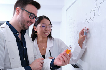 Two pharmacist researchers comparing two medicine vials.