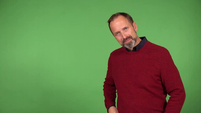 A middle-aged handsome Caucasian man waves at the camera with a smile - green screen background