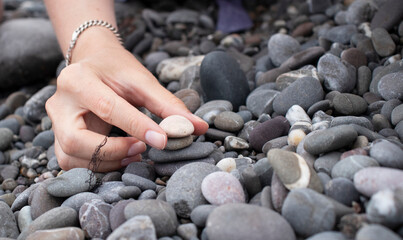 girl collects a cairn of stones by the sea in summer