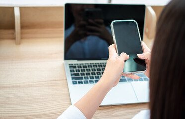 Happy beautiful asian woman working on a laptop and smartphone at the home office sitting at table. Happy female professional freelancer online using notebook pc and smartphone concept.