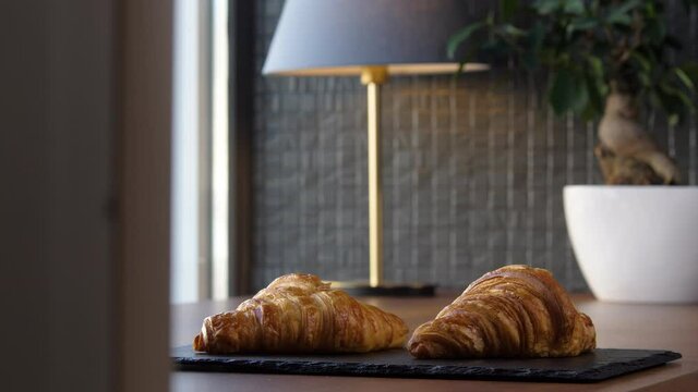 Two fresh delicious croissants on a tray on the table
