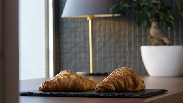 Two fresh delicious croissants on a tray on the table