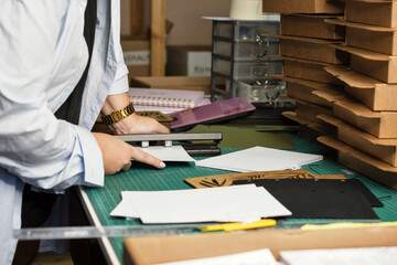 Female hands use hole punch to create perforations in removable paper blocks. Craft eco-friendly notebook in workshop. Small business concept.