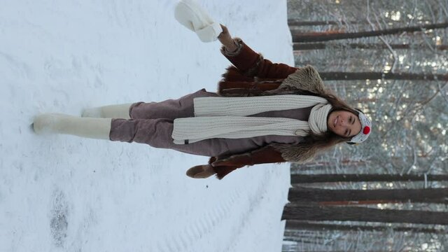 Happy brunette woman in winter wear posing in deer mask and walking on background of winter snowy forest. Vertical video