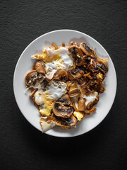 omelet with mushrooms in a white plate on a black table