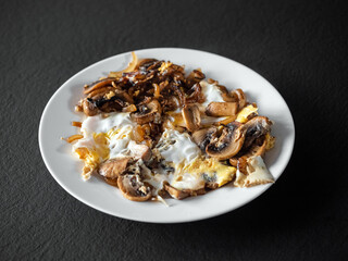 omelet with mushrooms in a white plate on a black table