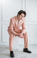 Portrait of Korean asian handsome smile friendly Business model man in pink suit sitting , business...