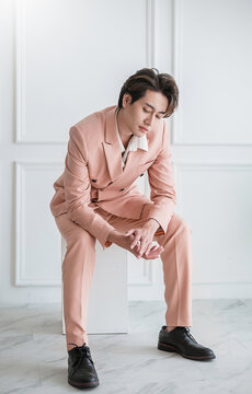 Portrait of Korean asian handsome smile friendly Business model man in pink suit sitting , business man smart with success, manager or executive with leadership office fashion workspace.