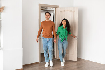 Portrait of excited emotional couple walking in their apartment