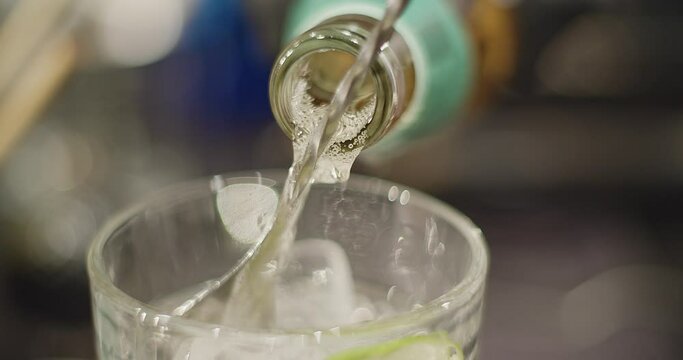 Cocktail series. Bartender preparing a Peruvian cocktail called Pisco Sour, in a bar with a relaxed atmosphere in slow motion, add ice, lime and mix the drink wearing black gloves as biosecurity.