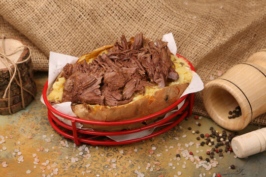 Baked kumpir potato stuffed with the cheese, sausage, olives, peppers and corn