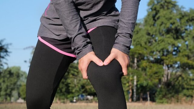 Athlete woman massage leg with thigh muscles pain during running training outdoors. Closeup of female runner touching leg in muscle pain. Muscle sports injury.