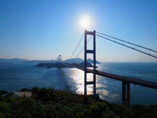 太陽がある青空と海峡に架かる吊り橋