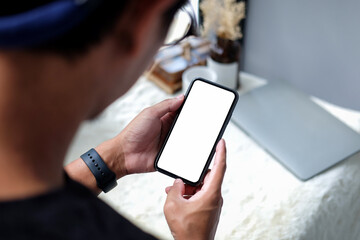 Over shoulder view of young man holding smart phone with blank screen.
