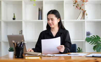 Successful businesswoman holding document and working with computer laptop.