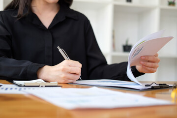 Businesswoman signing on document at her office desk.