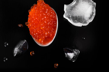 Spoon with red caviar on a black background