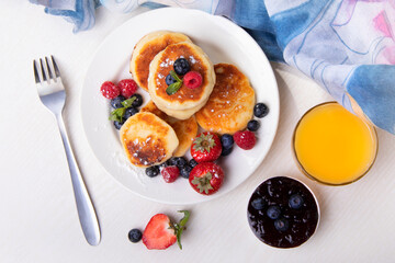 Cottage cheese pancakes with berries on a white plate on the table