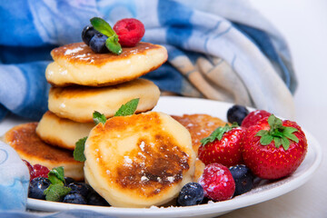 Cottage cheese pancakes with berries on a white plate on the table