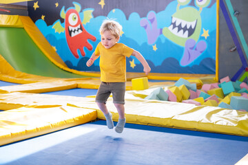 cute blond little boy jumps in a trampoline park, children activity
