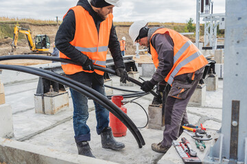 Two electrician builder workers installing high-voltage cable