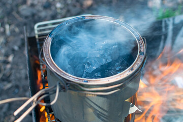Melting black tar over fire in a can of smoke