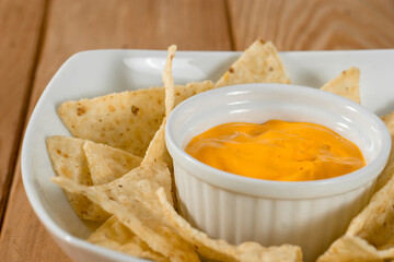 Cheddar on a bowl of nachos on a wooden table. The background is grey. Vertical image