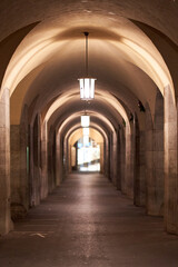 Obraz premium Urban lantern in a building avenue at night. Architecture with round vault and columns. Depth blur.