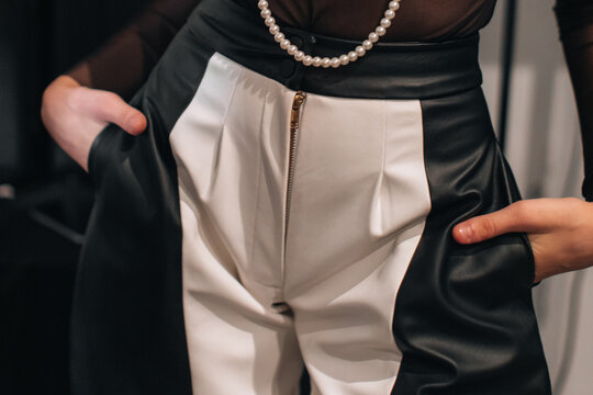 Cropped figure of fashion model woman wearing creative black and white pants with zipper. Fashion stylish female clothes concept.