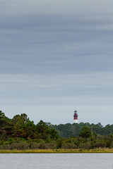 Chincoteague lighthouse standing above the trees guarding the beach on Chincoteague Island within Assateague National Seashore with an oncoming storm in the background.