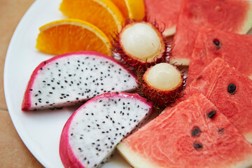 Sliced watermelon, oranges and tropical fruits on a plate