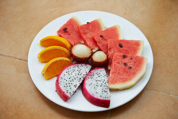Sliced watermelon, oranges and tropical fruits on a plate