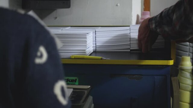 Hand preparing paper production, print shop. Work in progress, slow motion of team work
