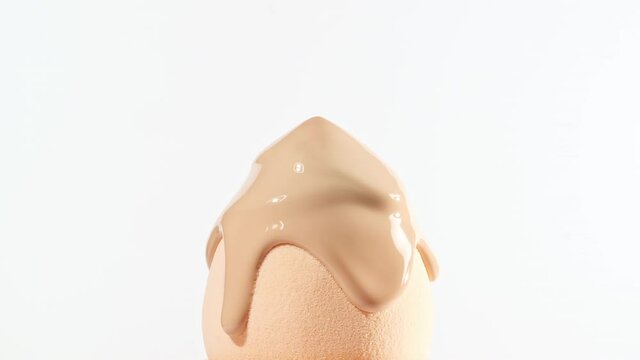 Make-up liquid beige foundation pouring on sponge, closeup. Cosmetic Dripping bb Cream on makeup brush on white background. Macro Shot. Beautiful Makeup concept. High quality 4k footage