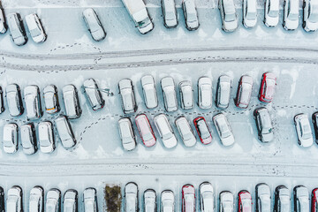 Aerial top view parked snow covered cars. Many snowy cars on the parking at the winter snowfall