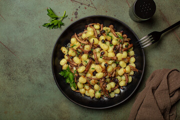 Potato gnocchi with black poplar mushroom or pioppini, onion and parsley. Copy space.
