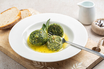 Eating canederli with spinach served with melted butter and sage. Bread dumplings made from dried bread, milk, spinach, cheese and eggs. Trentino food, Italy.