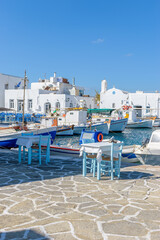 Fototapeta na wymiar Traditional Cycladitic view with moored traditional fishing boats at the picturesque harbor of Naousa Paros, Greece.