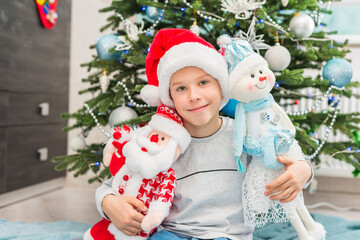 Christmas happy child under Xmas tree with santa claus and snowman.