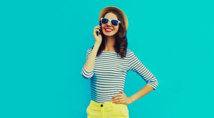 Portrait of happy smiling young woman calling on a smartphone on blue background