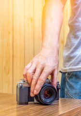 man hand picking up DSLR camera on desk to take a photo