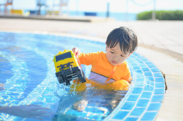 little baby boy enjoying swimming in a swimming pool in summer vacation.